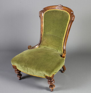 A Victorian mahogany show frame nursing chair upholstered in green material, raised on turned supports