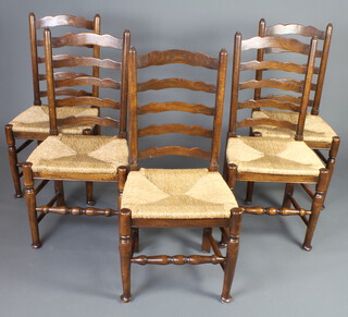 A set of 5 elm ladder back dining chairs with drop in woven rush seats, raised on turned supports 