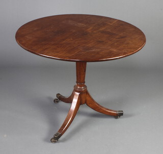 A 19th Century mahogany circular snap top tea table raised on a turned column and tripod base with brass caps and casters 69cm h x 86cm diam. 