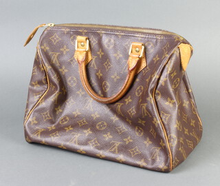 Louis Vuitton, a lady's canvas handbag complete with padlock and key and leather handles, decorated with Louis Vuitton monogram and logos and with serial number SP1904  23cm h x 30cm w x 18cm d 