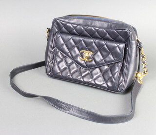Chanel, a lady's vintage Chanel navy blue quilted leather handbag with Chanel logo twist lock to the front, having a front pocket and red leather interior, gilt and leather strap, leather strand with gilt embossed Chanel logo ball, 20cm h x 29cm w x 9cm d 