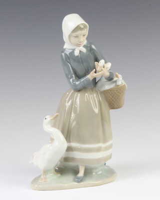 A Lladro figure of a girl carrying a basket of goslings, a goose at her feet 4568, 23 cm 