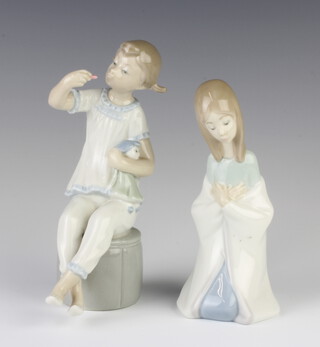 A Lladro figure of a kneeling girl 15cm, ditto of a girl sitting on a pouffe holding a doll 17cm 