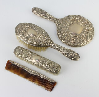 A repousse silver 4 piece brush set decorated with scrolls and flowers, Birmingham 1975 