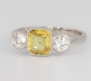 A platinum yellow sapphire and diamond ring, the centre cushion cut stone 1.5ct, the 2 brilliant cut diamonds 0.55ct, size M 