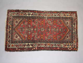 A red and tan ground Persian rug with 2 stylised diamonds to the centre 123cm x 72cm 