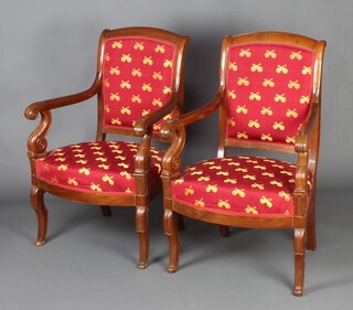 A pair of French Empire show frame mahogany open arm chairs, the seats and backs upholstered in red material, raised on turned supports 