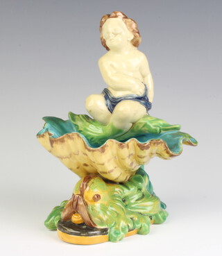 A Majolica table salt in the form of a child sitting on a shell supported by a dolphin 18cm 
