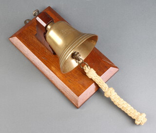 A brass wall mounted bell raised on a mahogany stand, marked "Metal from HMS Tiger Jutland 1916" 25cm x 13cm 