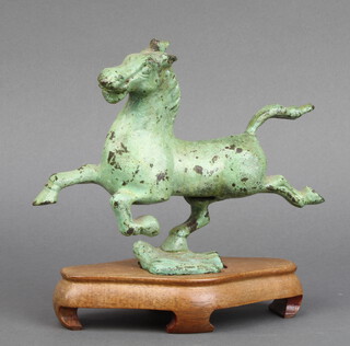 A Chinese bronze figure of The Flying Horse of Gansu, raised on a wooden base 15cm x 17cm x 4cm 
