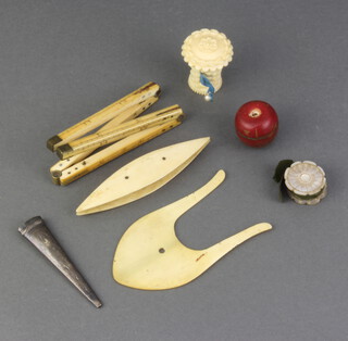 An ivory 4 section folding gauge 30.5cm, a Victorian carved ivory tape measure case in the form of a basket 3cm x 3cm, a stained ivory trinket box in the form of an apple 2cm x 2cm, a circular mother of pearl pin cushion in the form of a rose 1cm x 2cm, 2 ivory sewing implements and an engraved white metal scabbard clip
