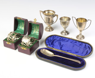 A pair of Edwardian pierced silver napkin rings cased, a cased spoon and 3 trophy cups