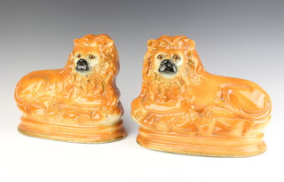 A pair of Staffordshire figures of reclining lions with glass eyes 23cm 
