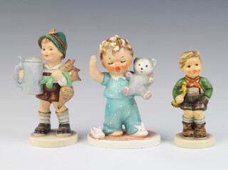 A Hummel figure of a child carrying a teddy bear BY1/11 13cm, a ditto of a boy carrying a stein no.87 14cm, another of a boy holding a bugle 97 11cm  