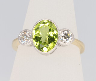 An 18ct yellow gold peridot and diamond ring, oval cut centre stone approx. 2ct flanked by brilliant cut diamonds approx. 0.45ct, size O