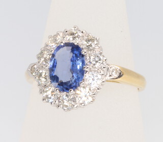 An 18ct yellow gold oval sapphire and diamond cluster ring, the centre stone approx. 1ct surrounded by brilliant cut diamonds, size N