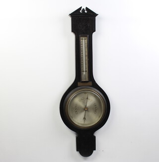 An aneroid barometer and thermometer with silvered dial contained in a carved dark oak wheel case with broken pediment 