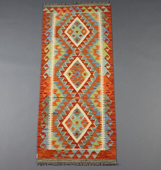 A terracotta, turquoise and blue ground Chobi Kilim runner with 3 stylised diamonds to the centre and a geometric all over design 151cm x 63cm 