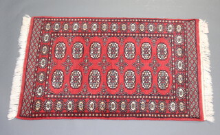 A red and white ground Afghan rug with 14 octagons to the centre within a multirow border 119cm x 76cm 