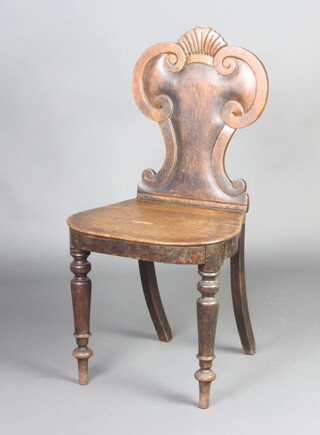 A Georgian oak hall chair with shield shape back and solid seat, raised on turned supports 
