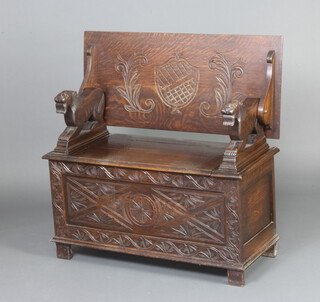 A carved oak monks bench with lion arms, the seat with hinged lid 72cm h x 91cm w x 41cm d 
