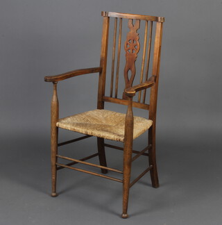A beech stick and wheel back carver chair with woven rush seat raised on turned supports 