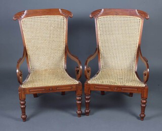 A pair of Victorian style Colonial mahogany framed open arm chairs with woven single cane seats and backs, raised on turned supports 