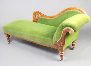 A Victorian carved mahogany show frame chaise longue upholstered in green material raised on turned supports 87cm h x 186cm w x 60cm d 