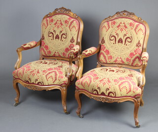 An impressive pair of 19th Century Italian carved walnut show frame open arm chairs with upholstered seats and backs, raised on cabriole supports 
