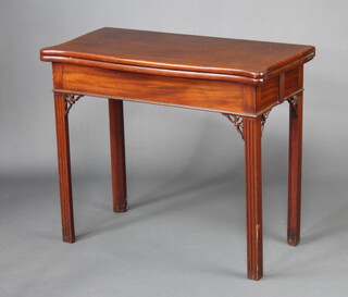A Georgian mahogany card table of serpentine outline, pierced frets to the sides, raised on square fluted supports 74cm h x 87cm w x 43cm d 