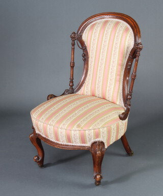 A Victorian walnut show frame nursing chair upholstered in pink and gold Regency stripe, raised on cabriole supports (frame loose) 
