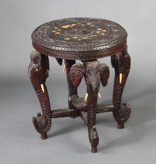 A circular carved Indian ebony occasional table raised on 4 elephant supports with X framed stretcher 55cm h x 46cm d 