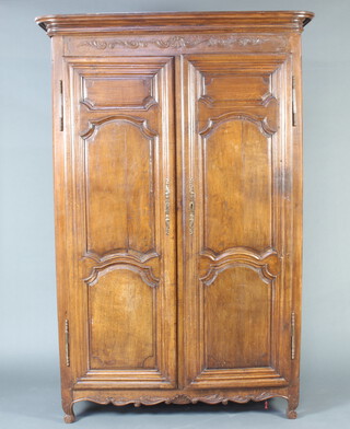 A French 17th/18th Century carved oak armoire with moulded cornice and shelved interior enclosed by a pair of panelled doors 215cm h x 244cm w x 56cm d 