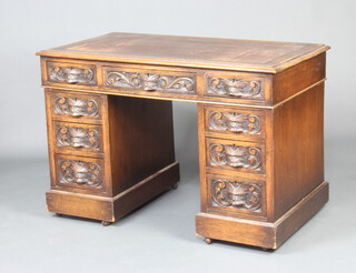 A Victorian carved oak kneehole pedestal desk with inset writing surface above 1 long and 8 short drawers with lion mask decoration 73cm h x 107cm w x 58cm 