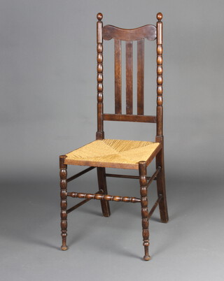 An Edwardian turned beech stick and rail back chair with woven rush seat and bobbin turned stretcher raised on turned supports