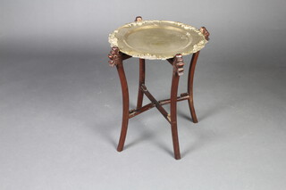 A Chinese circular brass and hardwood folding occasional table raised on outswept supports with engraved brass top decorated figures 58cm h x 47cm diam. 
