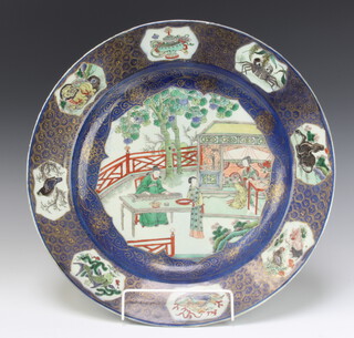 An 18th Century Chinese famille verte plate decorated with figures on a pavillion terrace enclosed by fish, birds, lions and plants 39cm 