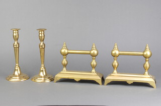 A pair of 19th Century circular brass candlesticks, raised on spreading feet with ejectors 22cm x 10cm, together with a pair of Victorian brass fire dogs 16cm x 20cm x 5cm 