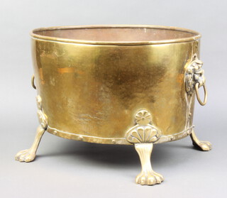 An oval planished brass twin handled planter with lion mask handles and paw feet 30cm h x 42cm w x 35cm d 
