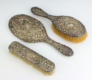 An Edwardian repousse silver oval hand mirror Birmingham 1902 and a similar hair and clothes brush 