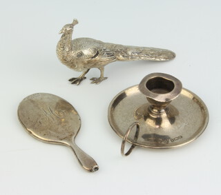 An Edwardian novelty miniature silver chamber stick Birmingham 1904, a ditto mirror Chester 1904 and a figure of a peacock 