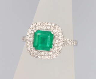 An 18ct white gold emerald and diamond cluster ring, the centre cushion cut stone approx. 1.24ct surrounded by brilliant cut diamonds 0.51ct, size M 