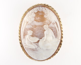 A large carved cameo brooch depicting two ladies beside a lake beneath trees, contained in a 9ct yellow gold frame, 77mm x 59mm, indistinctly signed 