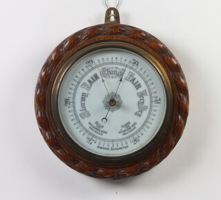 An Edwardian aneroid barometer with porcelain dial contained in a carved oak case with rope edge decoration 24cm diam. 