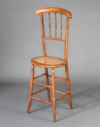 A child's 19th Century mahogany stick and bar back training chair with woven rush seat, raised on turned supports 