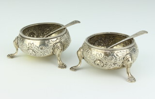 A pair of Victorian circular embossed silver salts raised on hoof supports together with matching spoons London 1885, maker Wakely and Wheeler, 161 grams (no liners) 