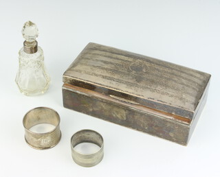 A rectangular silver cigarette box with hinged lid, cut glass dressing table bottle with silver collar, silver napkin ring, plated ditto 