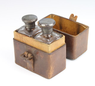 A matched pair of silver mounted toilet bottles contained in a fitted leather case London 1908 and 1909 