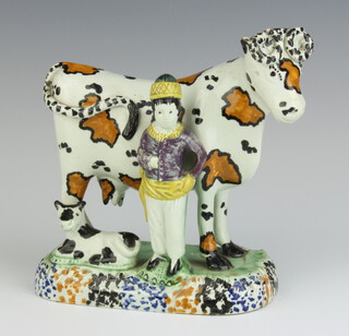 An 18th Century faience figure group of cow and herdsman, raised on an oval base 13cm x 14cm x 7.5cm 