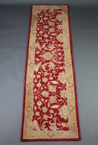 A red and gold patterned machine made floral runner 272cm x 79cm 